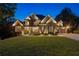 Picturesque brick and stone home with manicured lawn and landscape lighting provides stunning curb appeal at twilight at 5114 Brendlynn Dr, Suwanee, GA 30024