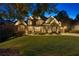 Elegant stone and brick home surrounded by trees featuring professional landscape lighting for enhanced curb appeal at 5114 Brendlynn Dr, Suwanee, GA 30024
