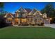 Stately brick and stone home with manicured lawn and professional lighting, showcasing curb appeal and inviting ambiance at 5114 Brendlynn Dr, Suwanee, GA 30024