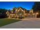 Elegant stone and brick home with a spacious driveway and a well-manicured front lawn at dusk at 5114 Brendlynn Dr, Suwanee, GA 30024