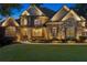 Beautiful stone and brick home with manicured front yard and landscape lighting against a twilight sky at 5114 Brendlynn Dr, Suwanee, GA 30024