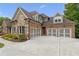 Home featuring a three-car garage, brick and stone exterior, and a long driveway leading to the entrance at 5114 Brendlynn Dr, Suwanee, GA 30024