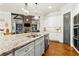 Spacious kitchen featuring a large granite island, stainless steel appliances, and modern lighting fixtures at 5114 Brendlynn Dr, Suwanee, GA 30024