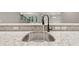 Close up of a kitchen sink with running water, stainless steel faucet, and granite countertop at 5114 Brendlynn Dr, Suwanee, GA 30024