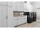 Laundry room with storage cabinets, granite countertop, a utility sink, and modern washer and dryer at 5114 Brendlynn Dr, Suwanee, GA 30024