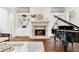 View of a piano and fireplace in the living room featuring hardwood floors and built-in shelving at 5114 Brendlynn Dr, Suwanee, GA 30024