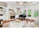 Spacious living room with built-in shelves, a cozy fireplace, and a grand piano at 5114 Brendlynn Dr, Suwanee, GA 30024