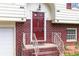 Close-up of a home's entryway highlighting a brick facade, red front door, white railings and meticulous landscaping at 2831 Carolyn Se Dr, Smyrna, GA 30080