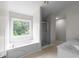 Bright bathroom featuring a garden tub, separate shower, and a large window at 1722 Preserve Creek Way, Loganville, GA 30052
