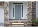 Close-up of a welcoming front entrance with a stone surround and a stylish gray door at 1722 Preserve Creek Way, Loganville, GA 30052