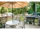 Back deck with umbrella, table and chairs and Blackstone grill overlooking wooded backyard at 4565 Deerfield Dr, Cumming, GA 30028