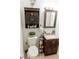 Well-lit bathroom with a dark vanity, a toilet, and a decorative mirror, creating a functional and stylish space at 4565 Deerfield Dr, Cumming, GA 30028