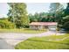 Charming single-story home with red metal roof, a garage, and a circular driveway at 4565 Deerfield Dr, Cumming, GA 30028