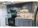 Modern kitchen featuring grey cabinets, granite countertops, and sleek, black appliances at 4565 Deerfield Dr, Cumming, GA 30028