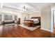 Spacious main bedroom with hardwood floors, tray ceiling, sitting area and a large window at 6350 Old Wood Hollow Way, Buford, GA 30518