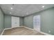 Finished basement featuring green walls, laminate flooring, drop ceiling, and double doors at 90 Barrington Grange Dr, Sharpsburg, GA 30277