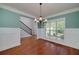 The dining room features hardwood floors, teal walls with white wainscoting, and a modern chandelier at 90 Barrington Grange Dr, Sharpsburg, GA 30277