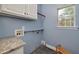 Functional laundry room with cabinetry, granite countertop, and a window at 90 Barrington Grange Dr, Sharpsburg, GA 30277