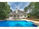 Sparkling pool with a covered porch, surrounded by mature trees, offers a private backyard retreat at 90 Barrington Grange Dr, Sharpsburg, GA 30277