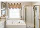 Bright bathroom features a separate glass shower, soaking tub, and window with blinds at 4401 Madison Woods Nw Dr, Marietta, GA 30064