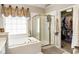 Bathroom showcasing tub, glass shower, window and door to huge walk-in closet at 4401 Madison Woods Nw Dr, Marietta, GA 30064