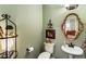 Stylish half bath featuring a pedestal sink, ornate mirror, and decorative accents at 4401 Madison Woods Nw Dr, Marietta, GA 30064