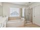Bathroom with white tub, glass shower and light-colored tiling at 4020 Emerald Glade Ct, Cumming, GA 30040