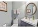 Half bathroom with a round mirror, sink, vanity and a decorative picture at 4020 Emerald Glade Ct, Cumming, GA 30040