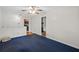Spacious living area with blue carpet leading to kitchen and view of stone fireplace at 1729 Norden Rd, Riverdale, GA 30296