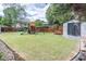 A spacious backyard including a green lawn, garden shed, tasteful landscaping, and playset at 220 Chandler Ct, Sugar Hill, GA 30518