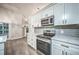 Modern kitchen with gray backsplash, stainless steel appliances, and bright white cabinets at 220 Chandler Ct, Sugar Hill, GA 30518