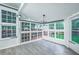Sunroom with large windows offering backyard views, gray floors, and a modern chandelier at 220 Chandler Ct, Sugar Hill, GA 30518