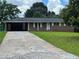 Charming single-story brick home with a long driveway and attached carport, nestled among mature trees at 6192 Meadowbrook Dr, Norcross, GA 30093