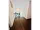 Hallway with hardwood floors, white walls, plants on a stand, and an artwork hanging on the wall at 5090 Bellehurst Ln, Cumming, GA 30040