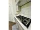 Close-up of a modern gas stovetop with stylish cabinetry and white subway tile backsplash at 5090 Bellehurst Ln, Cumming, GA 30040