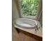 Close-up of a soaking tub with jets near a window with a view of green trees at 100 Hamilton Glen Ct, Fayetteville, GA 30215