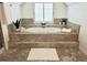 Bathroom featuring a luxurious soaking tub on a platform, neutral tile, and arched window at 1045 River Pt, Suwanee, GA 30024
