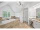 Bright bathroom featuring a luxurious soaking tub on a platform, vanity, and arched window at 1045 River Pt, Suwanee, GA 30024