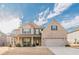 Inviting two-story brick home with a welcoming front porch and a manicured lawn and beautiful skies at 879 Tranquil Way, Hampton, GA 30228