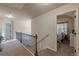 Hallway upstairs with iron railing and neutral tones offer an inviting transition to the bedrooms at 879 Tranquil Way, Hampton, GA 30228