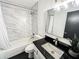 Modern bathroom featuring a tiled shower-tub, toilet, black countertop and rectangular mirror at 3150 Stratford Green Pl, Avondale Estates, GA 30002