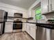 Kitchen boasts stainless steel appliances, white cabinetry, granite countertops, and grey wood-look floors at 3150 Stratford Green Pl, Avondale Estates, GA 30002