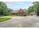 Beautiful red brick house with dormer windows, an attached garage, and a large, circular driveway surrounded by trees at 750 Old Loganville Road Southwest, Loganville, GA 30052