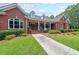 Red brick house with dormers, a covered porch with columns, lush landscaping, and a sidewalk leading to the front entrance at 750 Old Loganville Road Southwest, Loganville, GA 30052