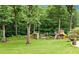 Backyard playground features a slide and rope bridge surrounded by a green lawn and mature trees at 217 Heritage Town Pkwy, Canton, GA 30115
