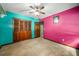 Colorful bedroom features teal and pink walls, ceiling fan, and closet space at 133 Sw Patterson Rd, Lawrenceville, GA 30044