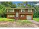 Split-level home boasts brown wood and brick facade, white trim, and an attached one car garage at 1991 Flat Shoals Rd, Riverdale, GA 30296