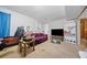 Spacious living room featuring neutral walls, carpet flooring, and a comfortable purple sofa at 1991 Flat Shoals Rd, Riverdale, GA 30296