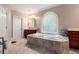 Bathroom featuring a large soaking tub with tile surround and an arched window at 3698 Lakeview Drive, Tucker, GA 30084