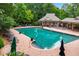 Community pool with brick surround, lounge chairs, umbrellas, and covered seating area at 5833 Wembley Dr, Douglasville, GA 30135